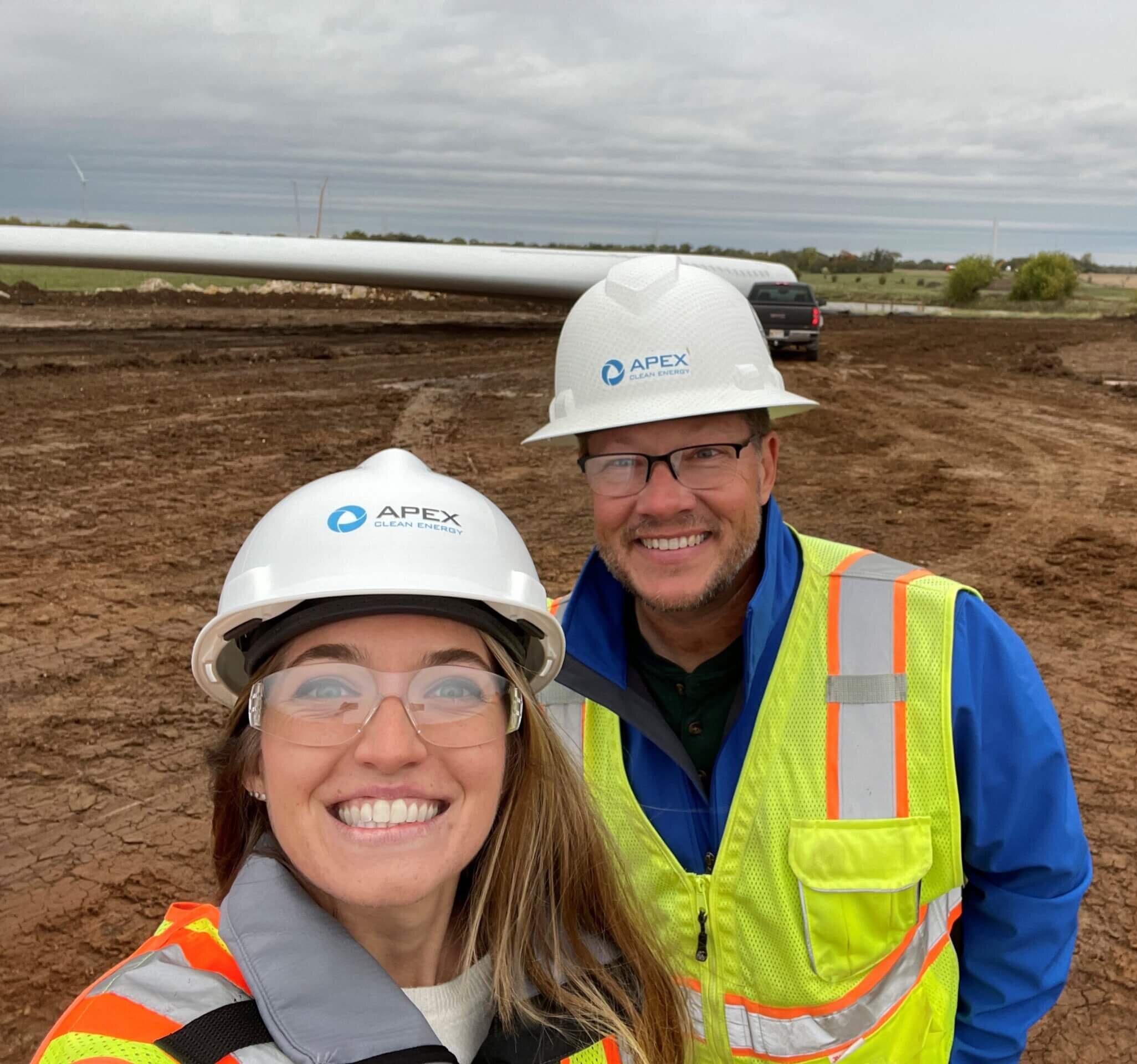 smiling people in hard hats on wind farm construction site
