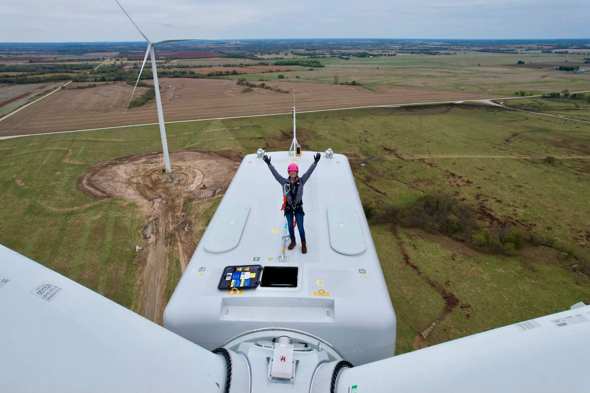 woman standing atop a wind turbine