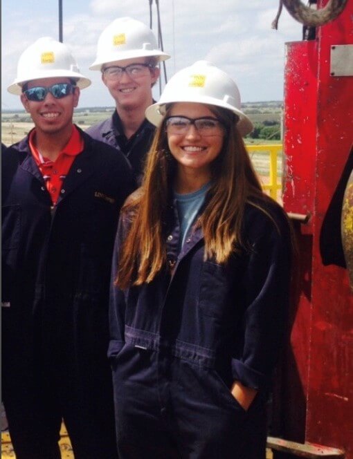 smiling people in hard hats on oil rig