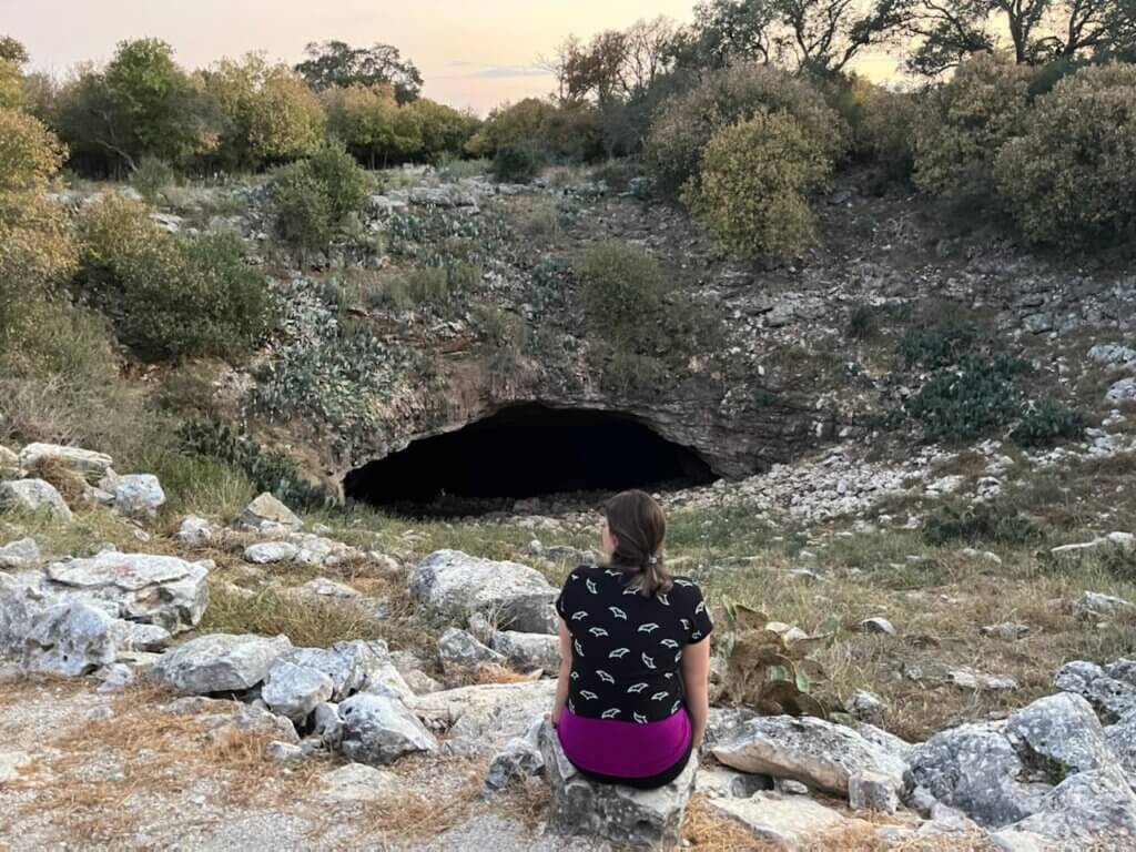 Woman sits outside cave