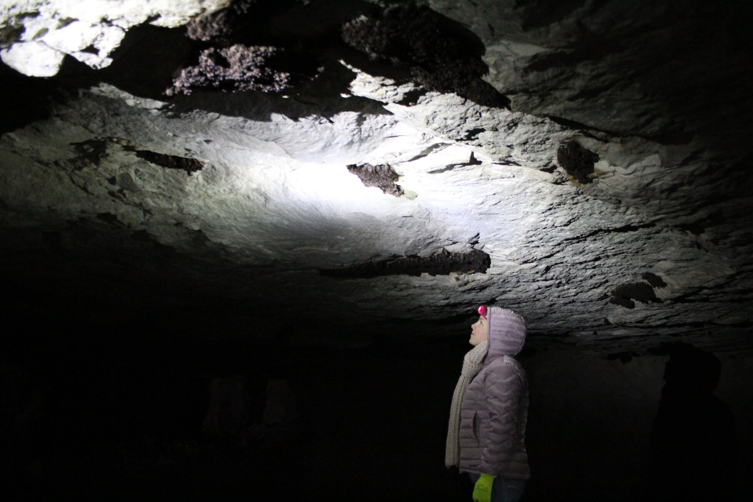 woman inside bat cave with headlamp